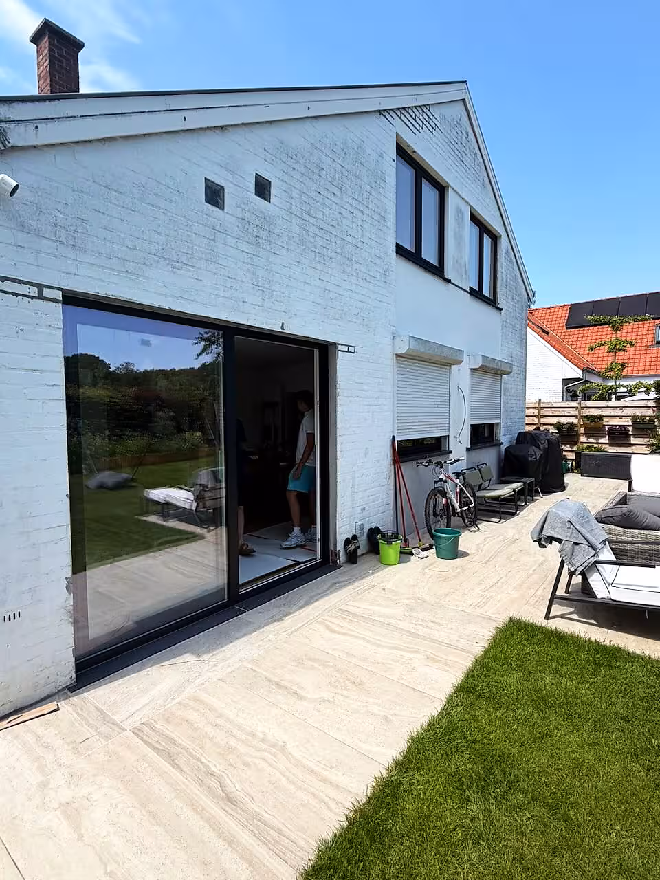 Baie coulissante à profilé noir ouvrant sur le jardin d’une maison aux murs blancs — réalisation Pulsar Windows