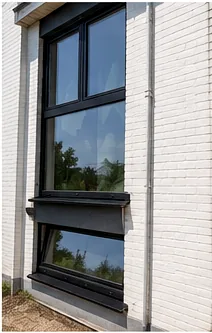 Fenêtre à cadre sombre installée sur une façade en briques claires.