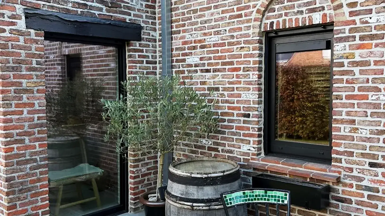 Black-framed windows on a renovated brick house with a terrace — a Pulsar Windows project